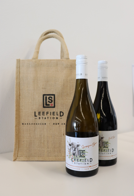 A bottle of Sauvignon Blanc and a bottle of Pinot Noir from Marisco Family Vineyards are elegantly presented in a LEEFIELD STATION TWO BOTTLE JUTE BAG, featuring the Leefield Station logo. The plain white background enhances the focus on this eco-friendly and stylish display.