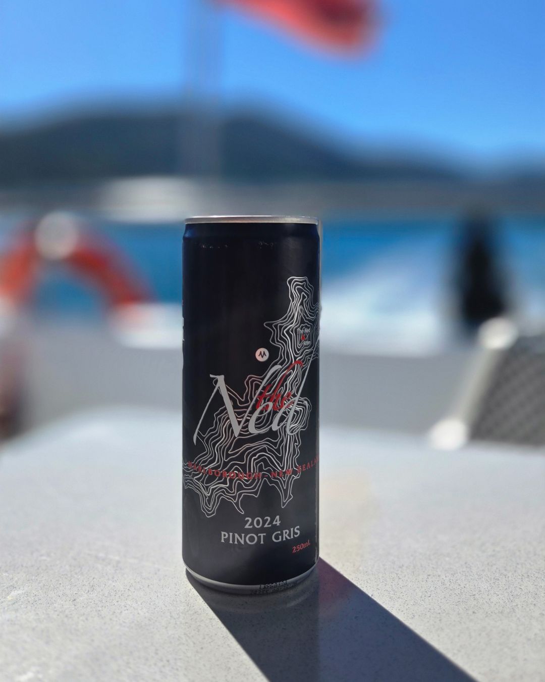 The Ned canned wine with 2024 Pinot Gris label on a blurred outdoor background, likely on a boat in the harbour